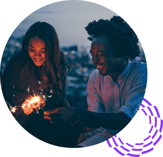 Woman and African American man holding sparklers on city roof