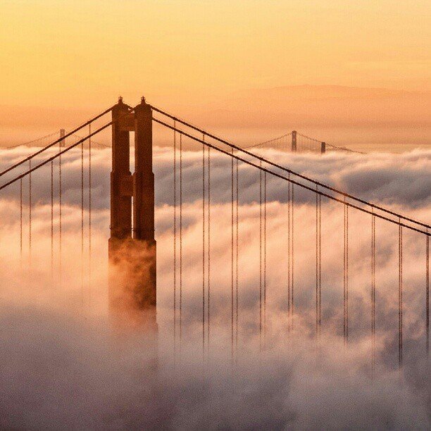 Top of a Golden Gate bridge surrounded by clouds