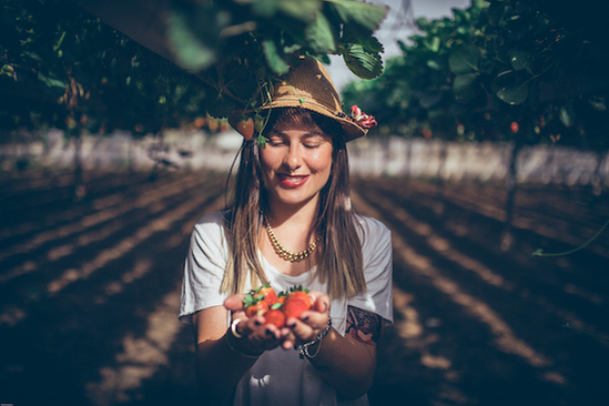 Woman smiling while holding strawberry's in strawberry field