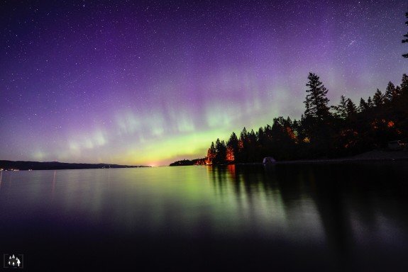 Northern lights above lake and trees