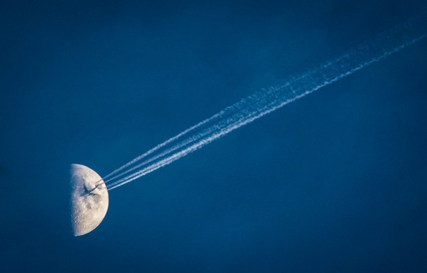 Plane in sky with the moon in the background