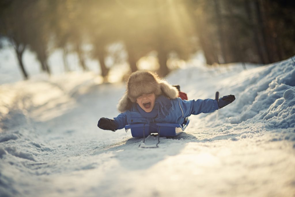Boy using sled outside in the snow