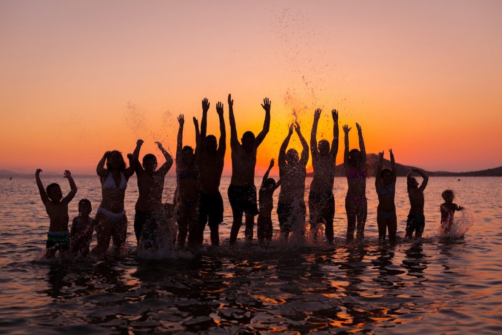 Group of people in the water at the beach with hands raised up