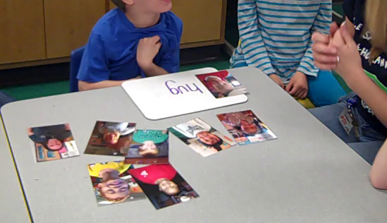 A student practices reading the word 'hug' with his teacher accompanied by pictures of his classmates.
