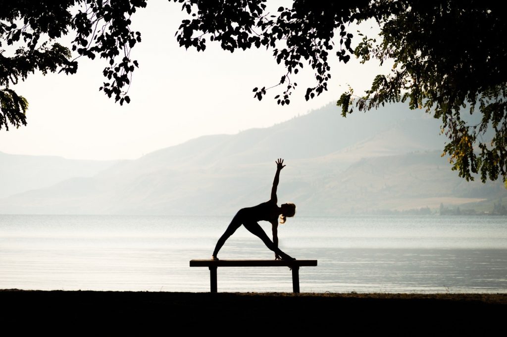 a woman in silhouette doing a yoga pose on a bench t20 zLBz4X