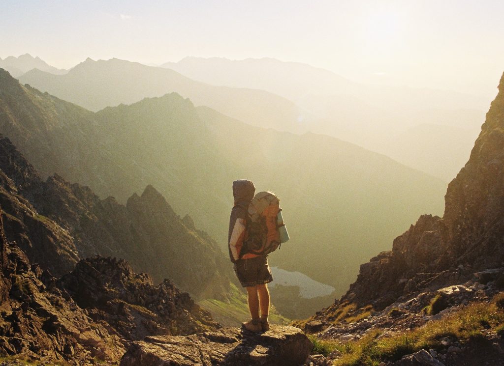 man standing on top of a mountain with a hiking backpack