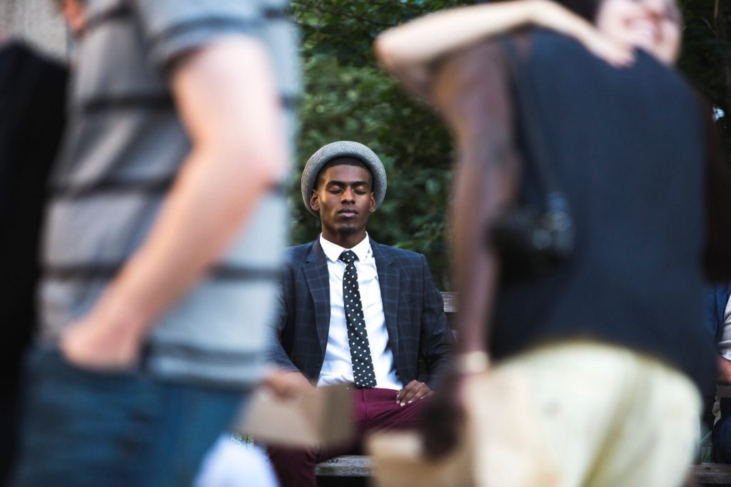 african man sitting on a bench with eyes closed