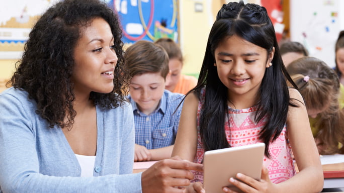 Teacher helping student on tablet