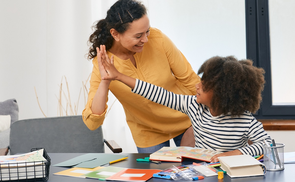 Female child psychologist giving high five to autistic child in psychotherapy session