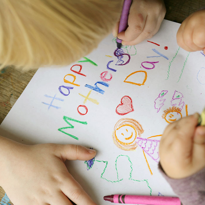 Child hand writing mother's day card