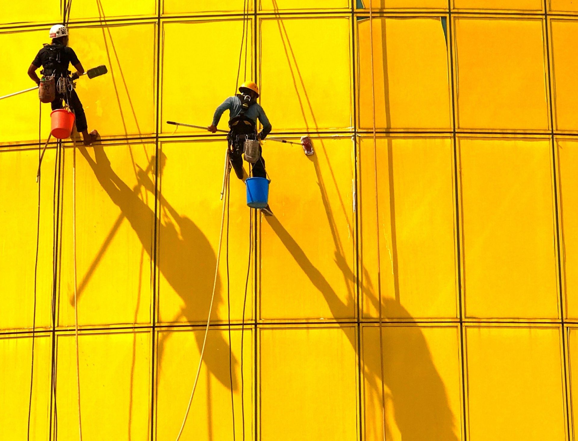 2 men scrubbing the facade of a yellow building singapore t20 nRrz78