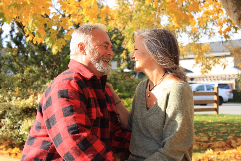 Elderly couple smiling at each other outside