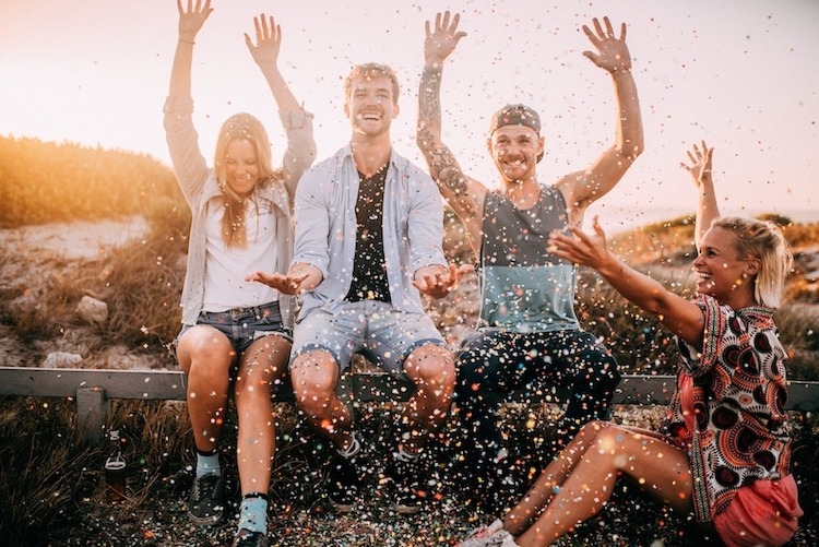 Group of people throwing confetti and smiling outside