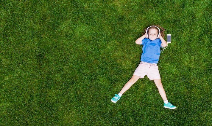 Child laying on grass with headphones on