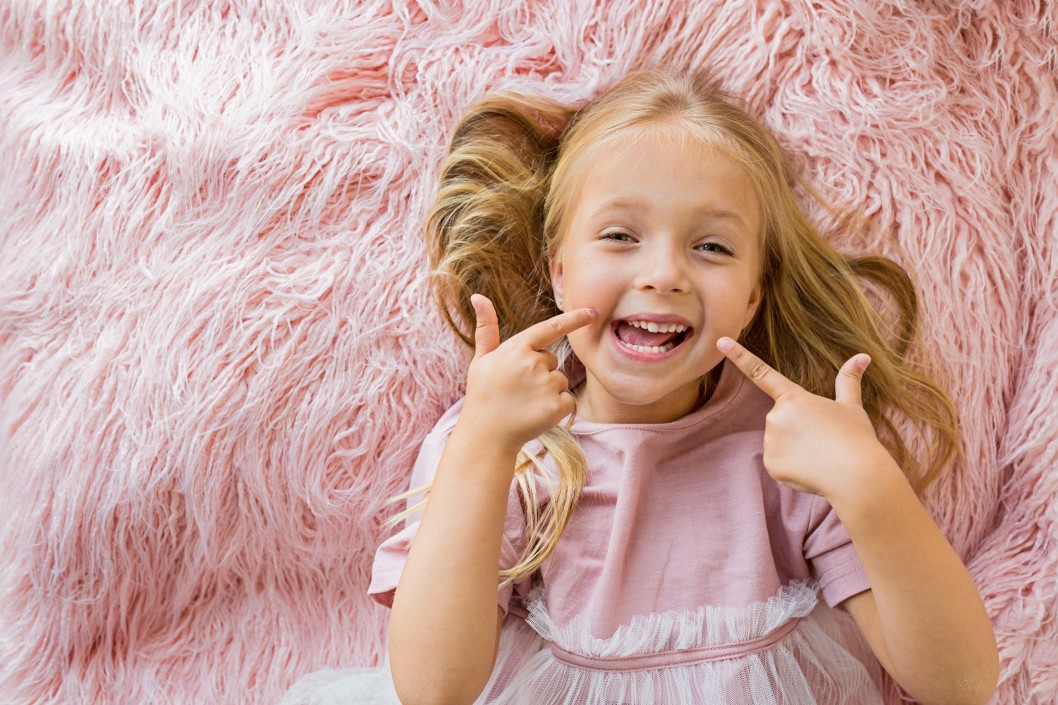 Young girl smiling while laying on fluffy bed