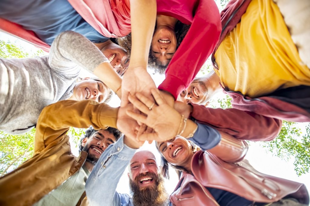 Directly below portrait of happy diverse large group of multicultural friends holding hands