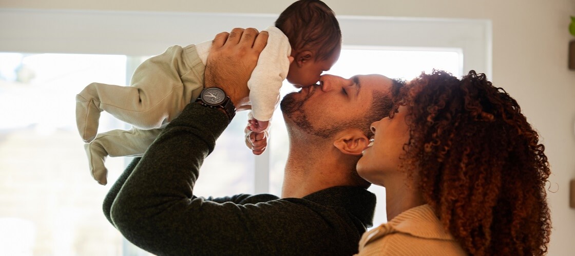 Young couple holding up newborn baby