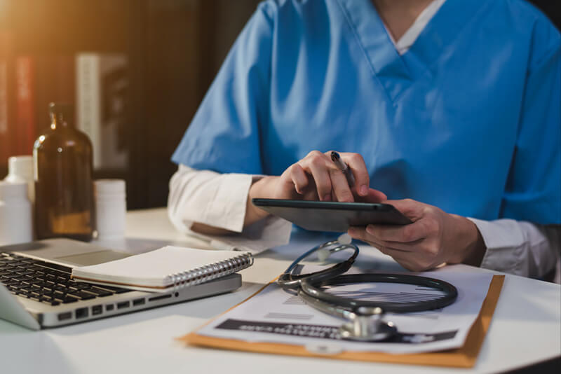 Doctor working on desk with laptop computer and paperwork in the office