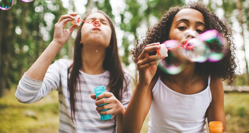 Girls blowing bubbles outdoors
