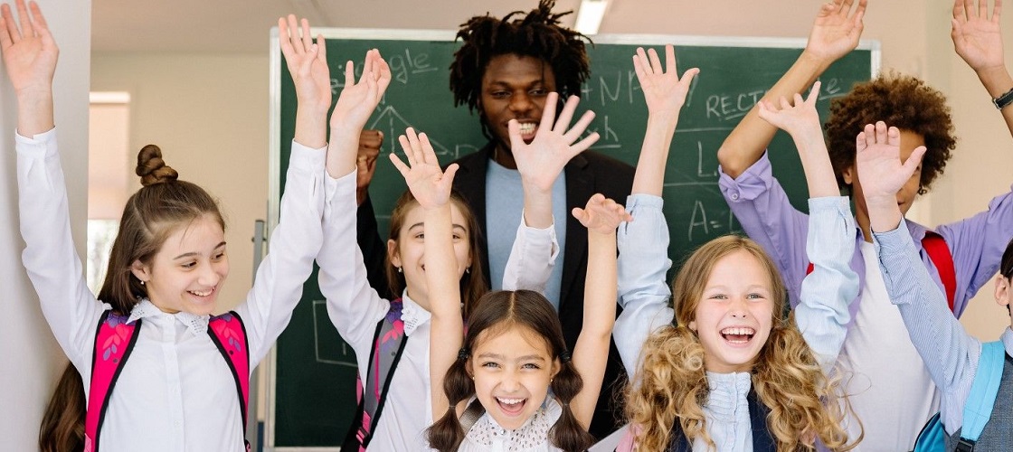 African American male teacher behind students in classroom cheering