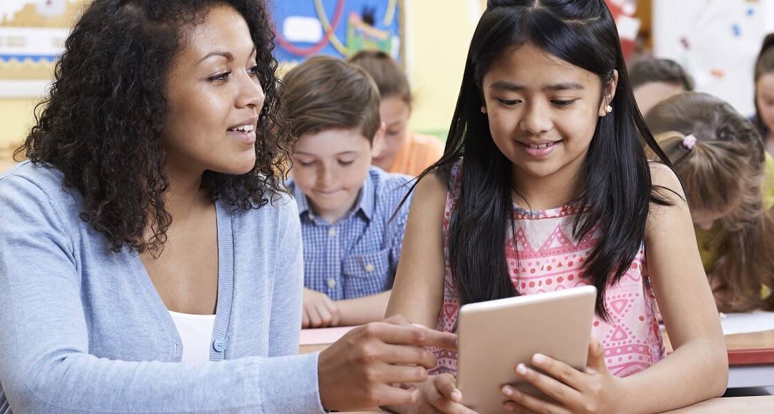 Teacher helping student on tablet