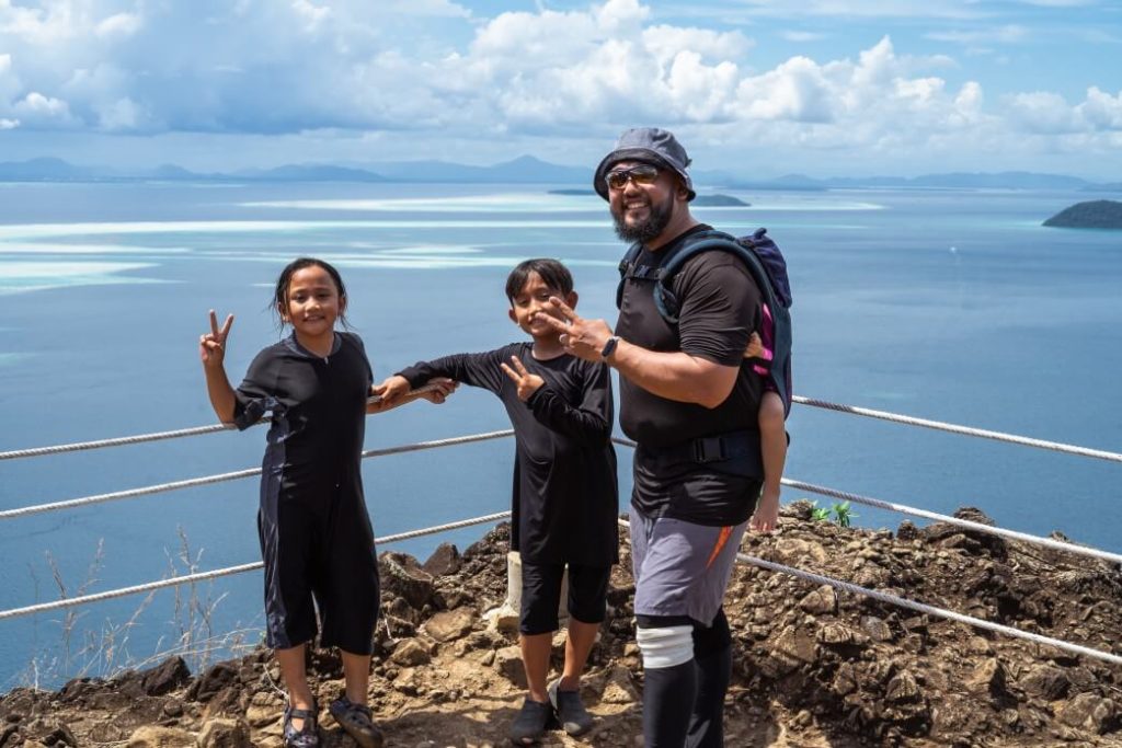 father and children posing on mountain trail overlooking ocean