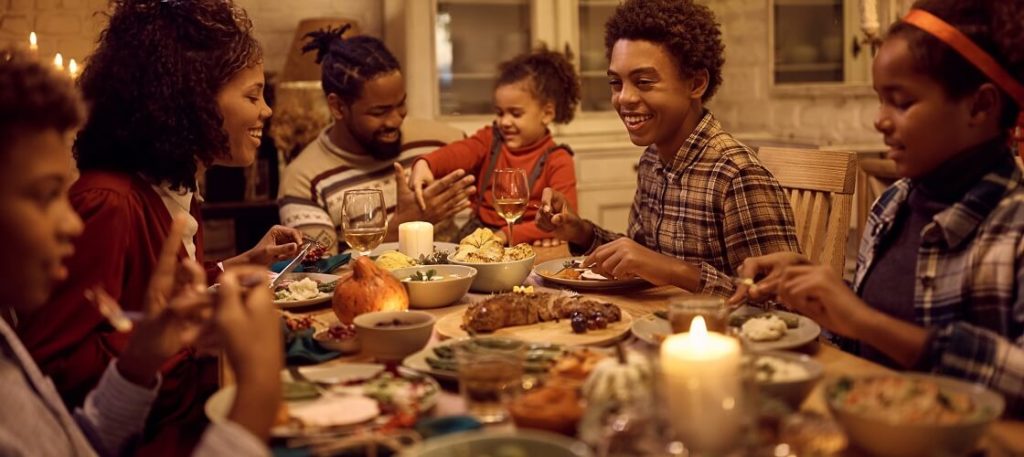 Happy African American family eating holiday dinner at dining table