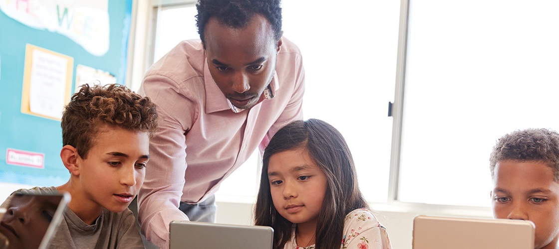 Male teacher with kids at computer