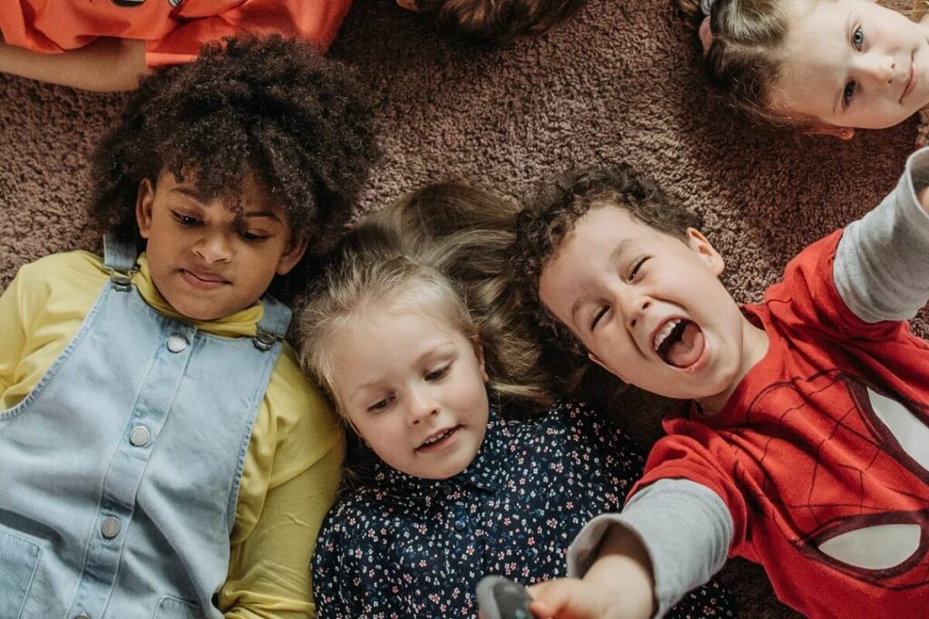 Happy children lying on a carpet head to head looking up