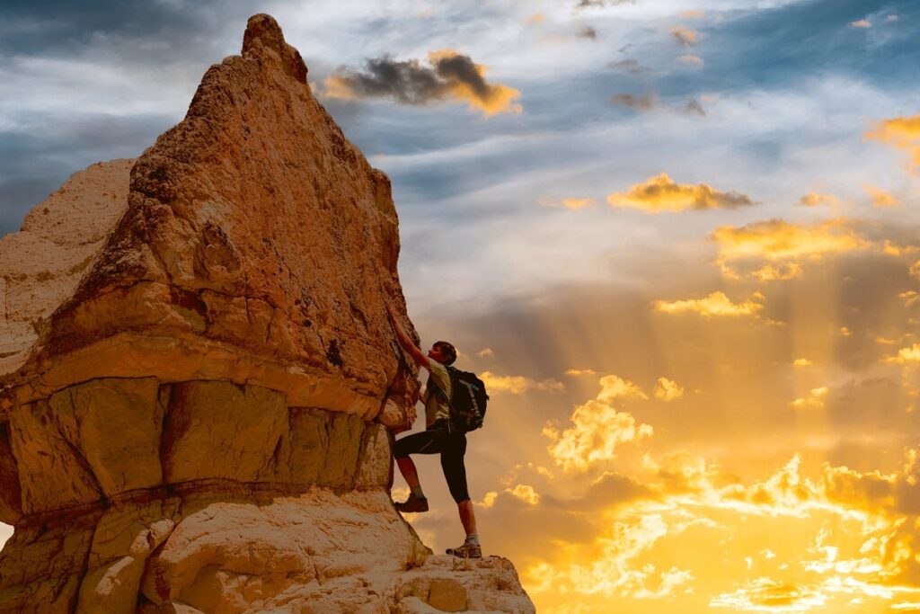 silhouette of successful woman climbing mountain during beautiful sunset