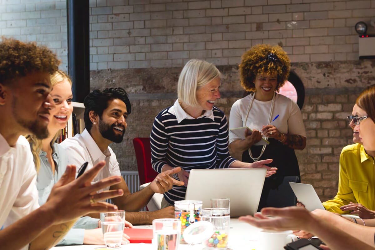 Group of business professionals in rustic modern office sit around table in positive discussion