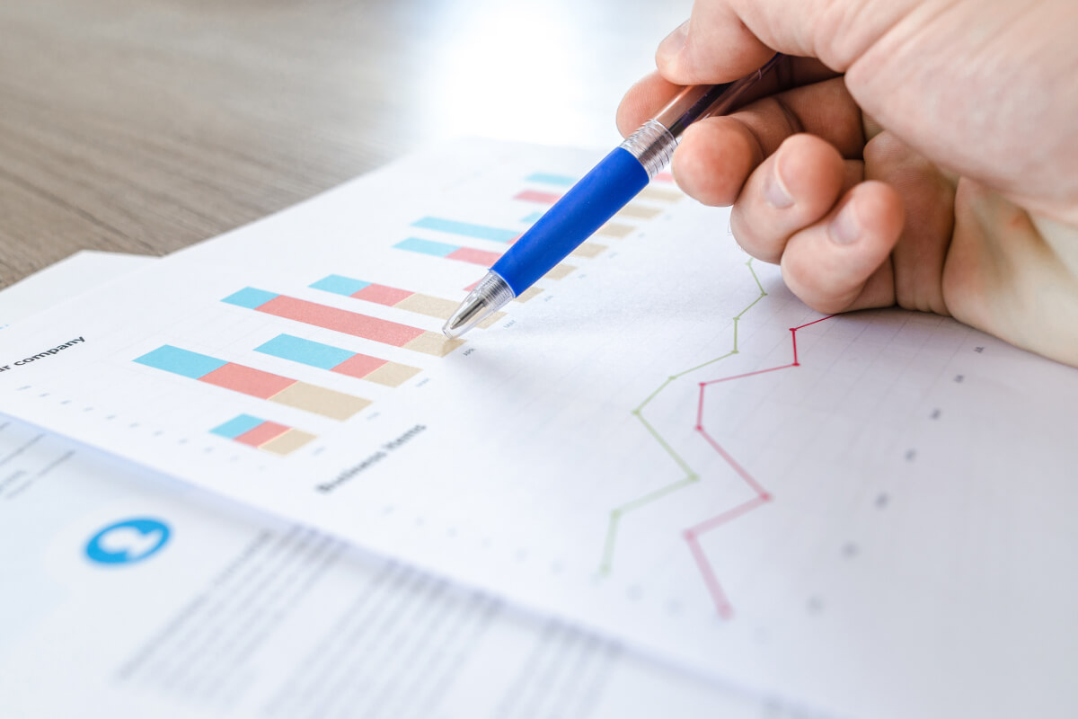 Close up of man pointing to printed out graphs business graph on wood table