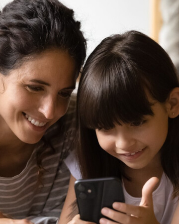 Mother and young daughter sharing smart phone