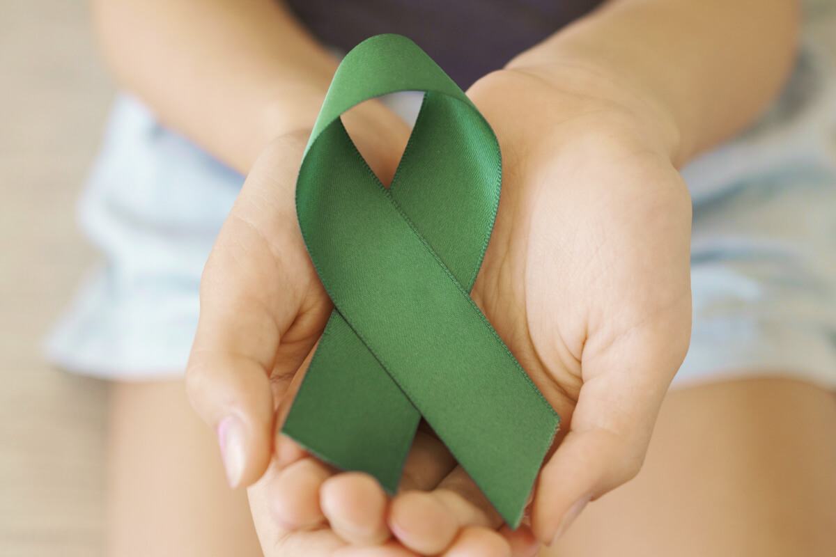 Hands holding green ribbon representing World Mental Health Day