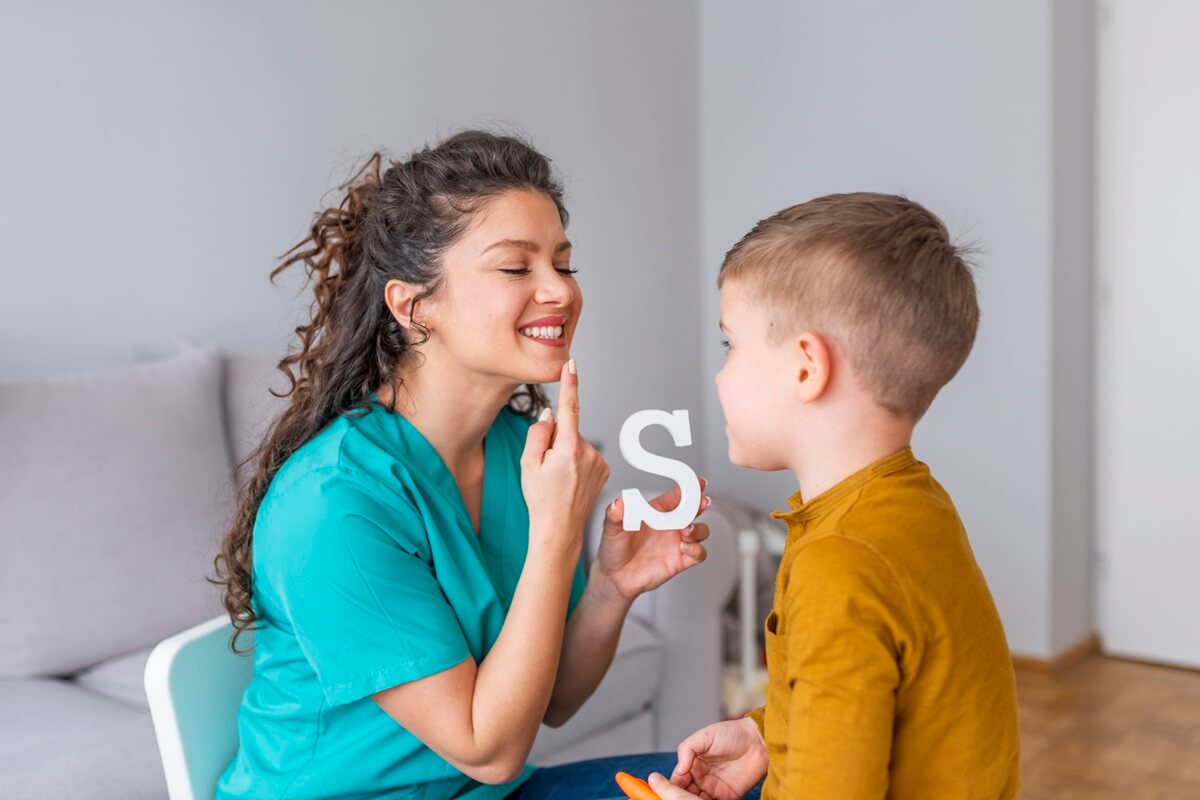 speech therapist holding letter S during session with little boy