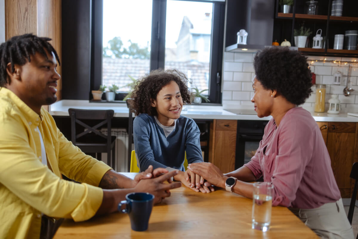 African American parents talking with teenage son at kitchen table