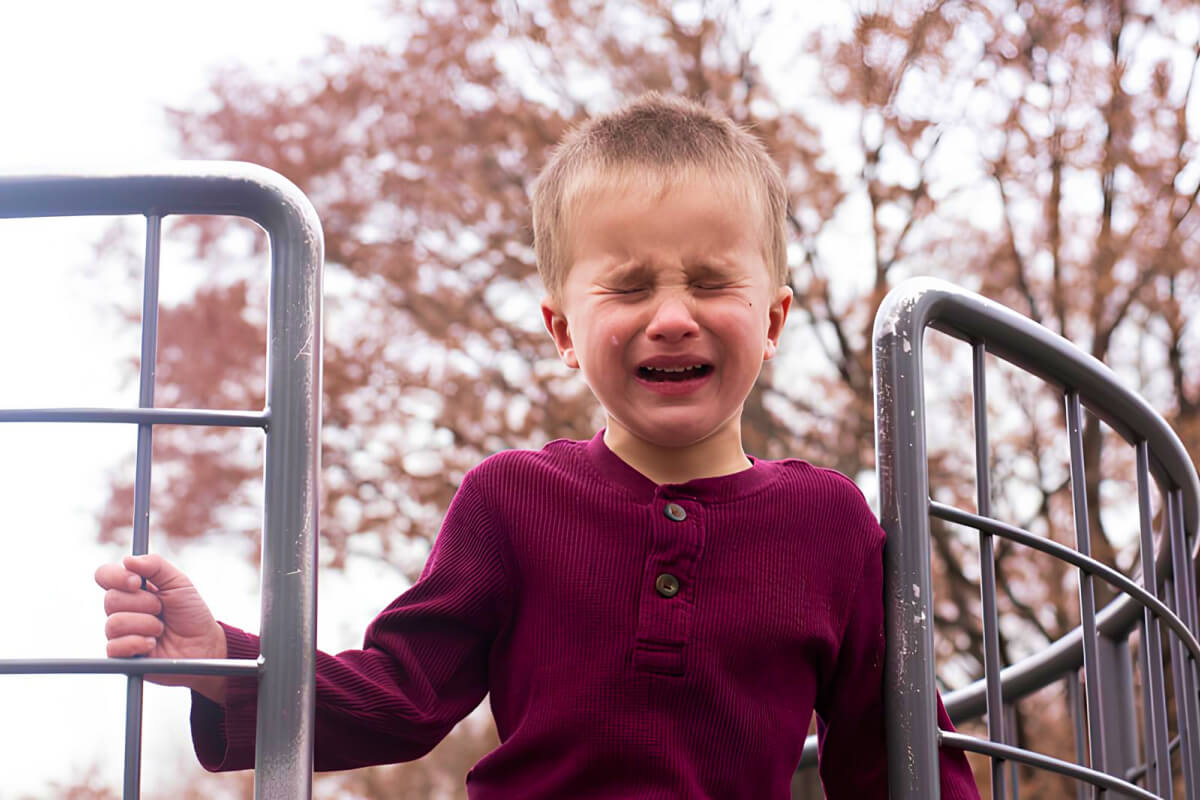 little boy crying at playground with tear rolling down cheek
