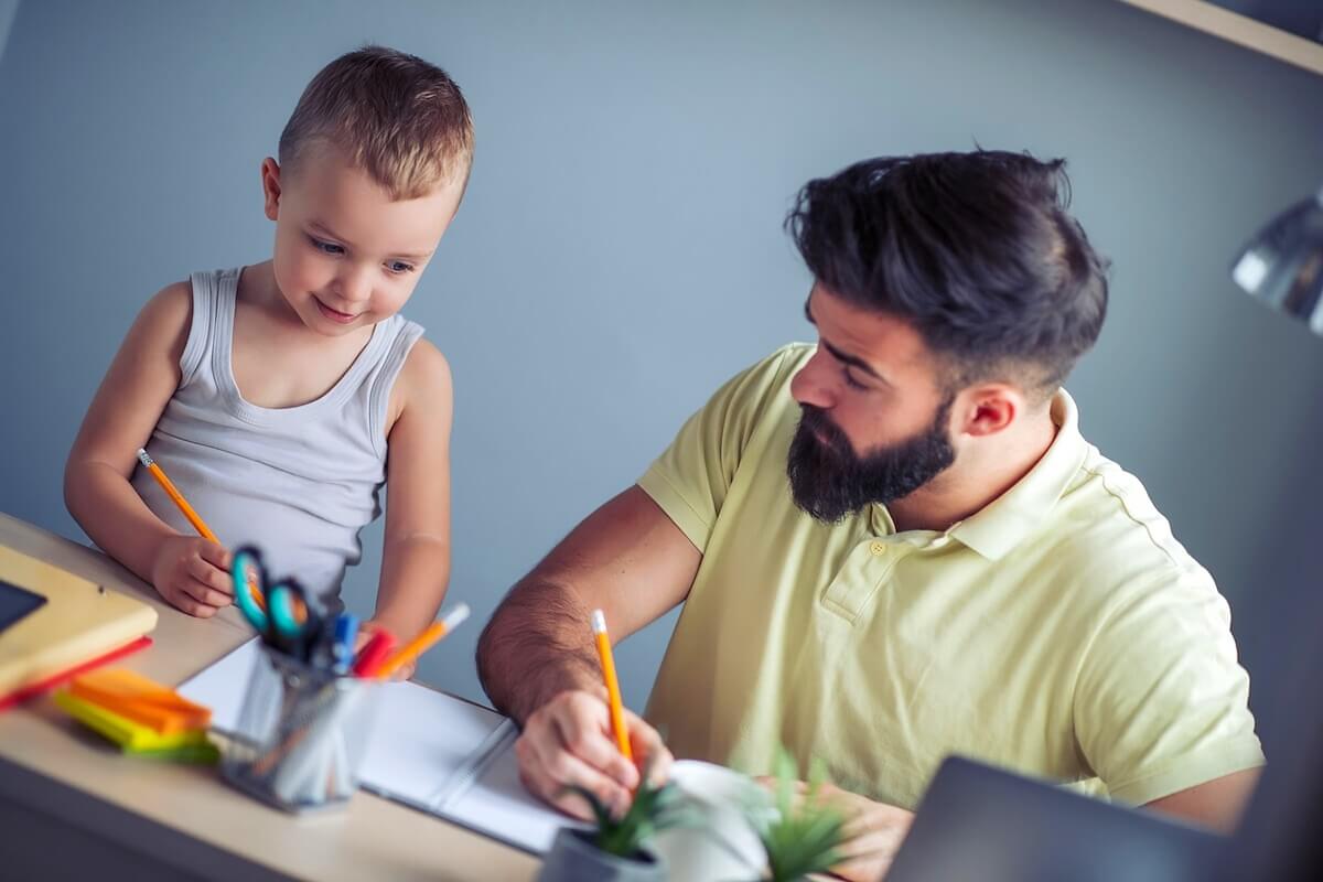 Male bearded ABA provider helping boy draw during session