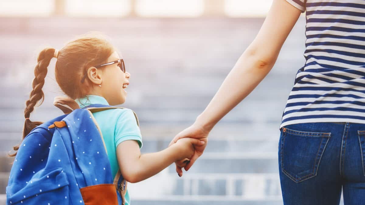 mother and daughter holding hands walking to school
