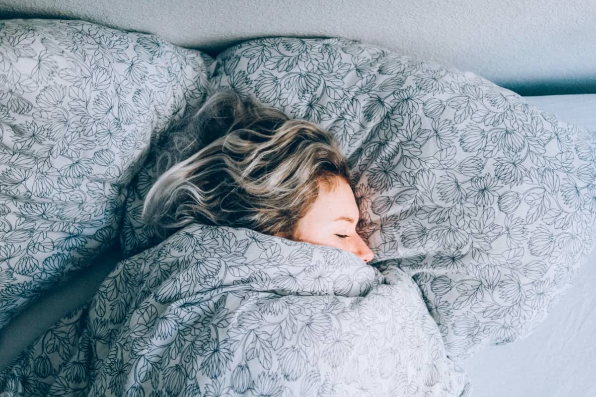 Woman sleeping in bed wrapped in covers