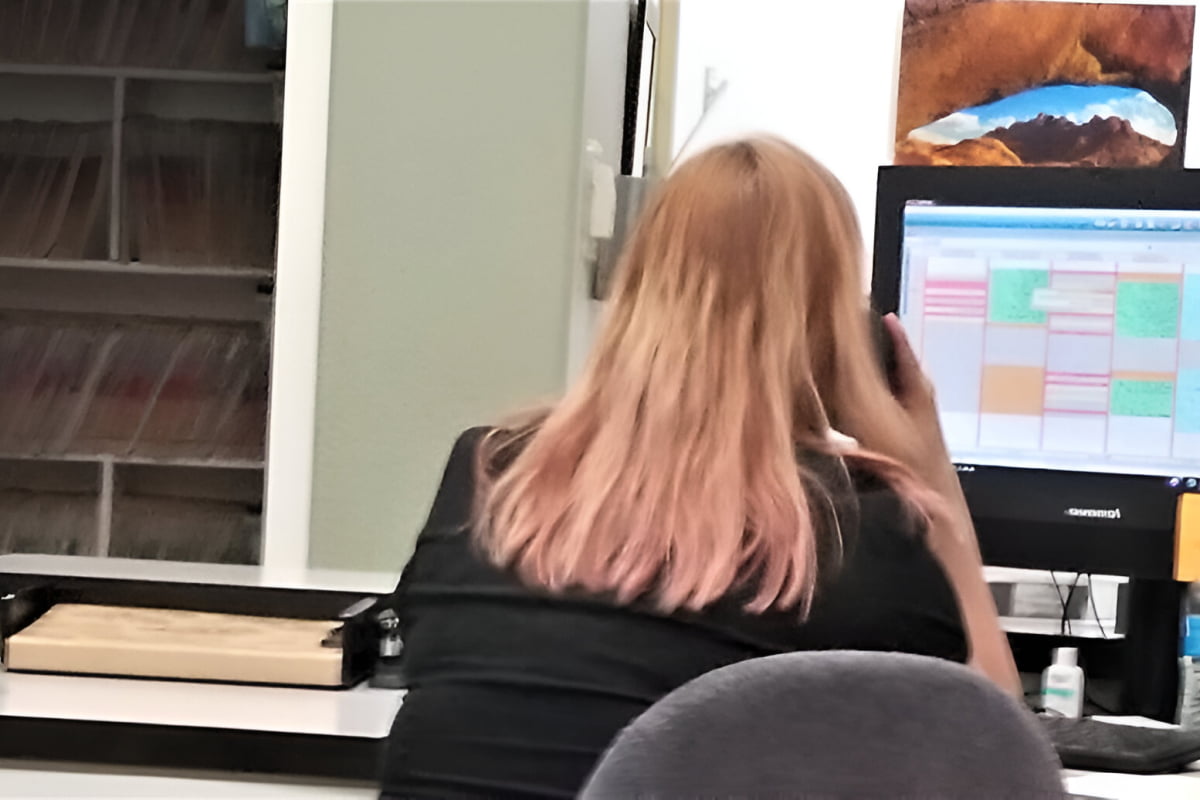 red haired ABA practice secretary at computer desk at work on the phone