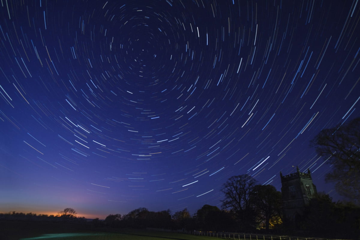 astronomy star trails in early spring above village church