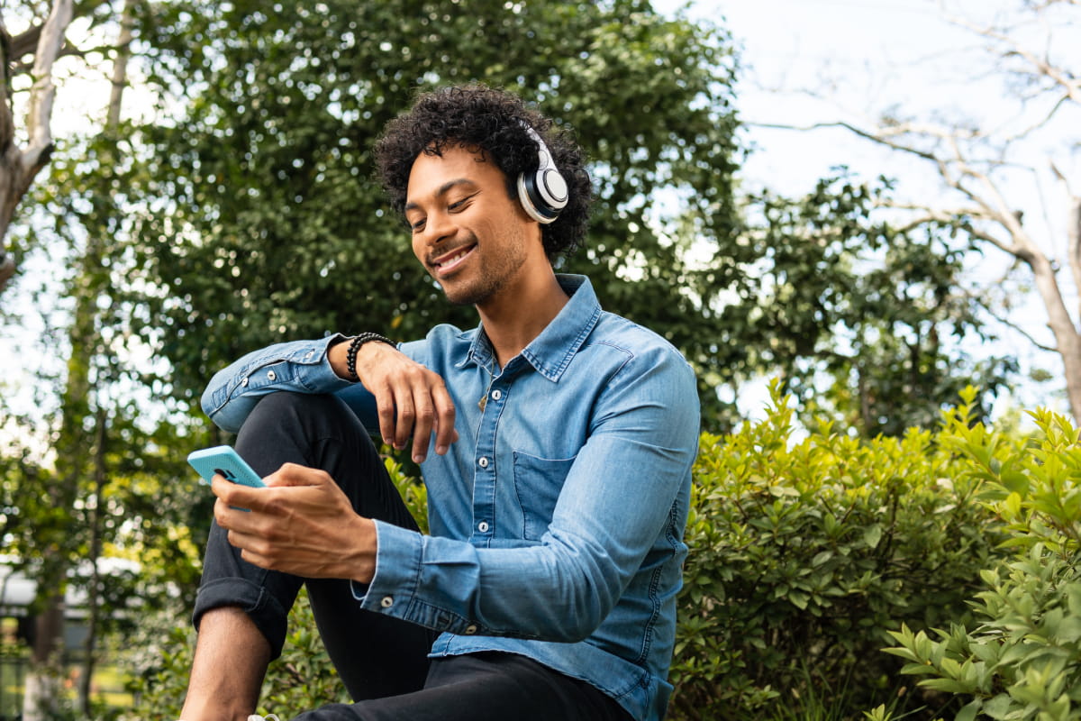 Man in woods wearing headphones using RethinkCare app on smartphone