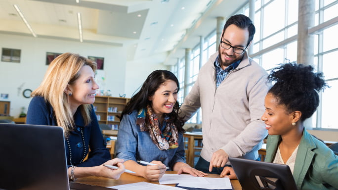 Diverse adult students talking during assignment in college study group