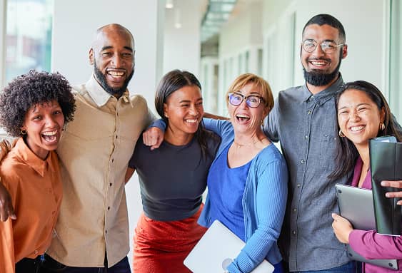 Group of Professionals Smiling and Standing Together in Office Corridor.