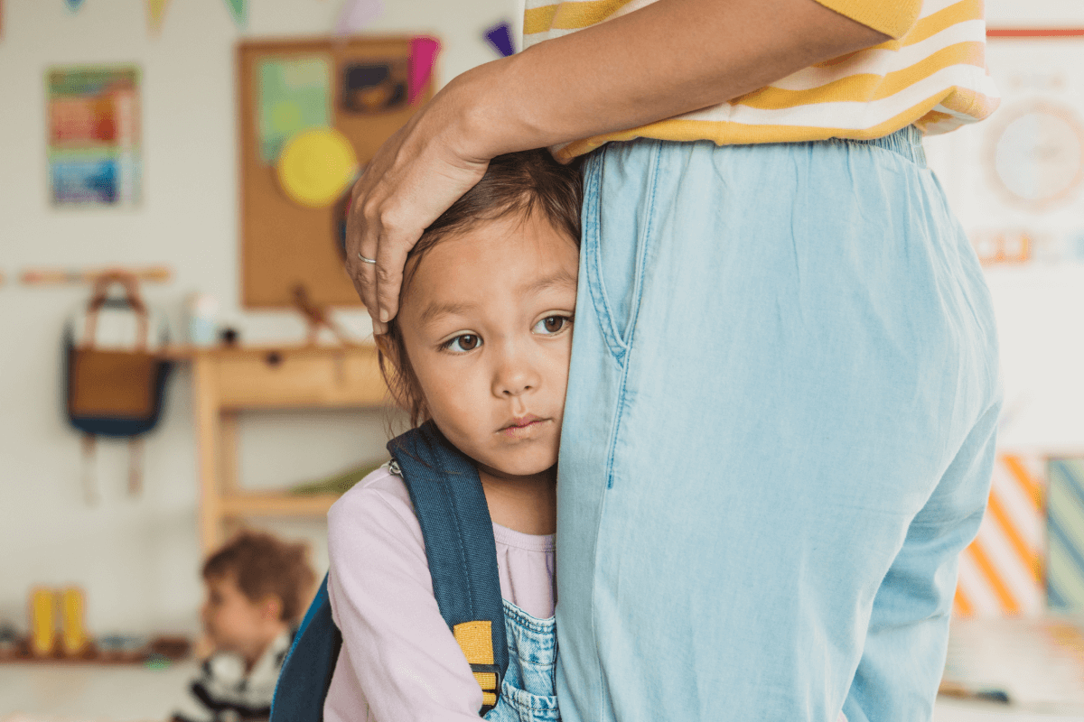 Worried child clinging to a parent in a classroom