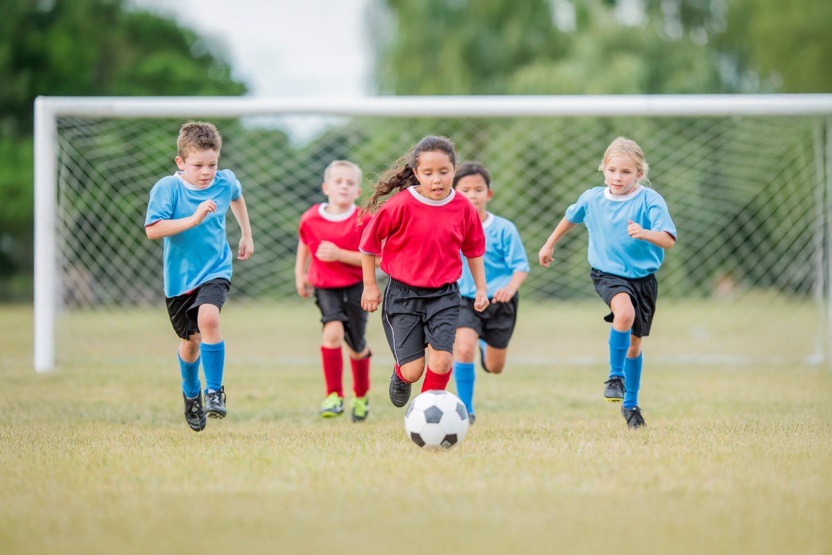 Young children playing soccer on a grassy field