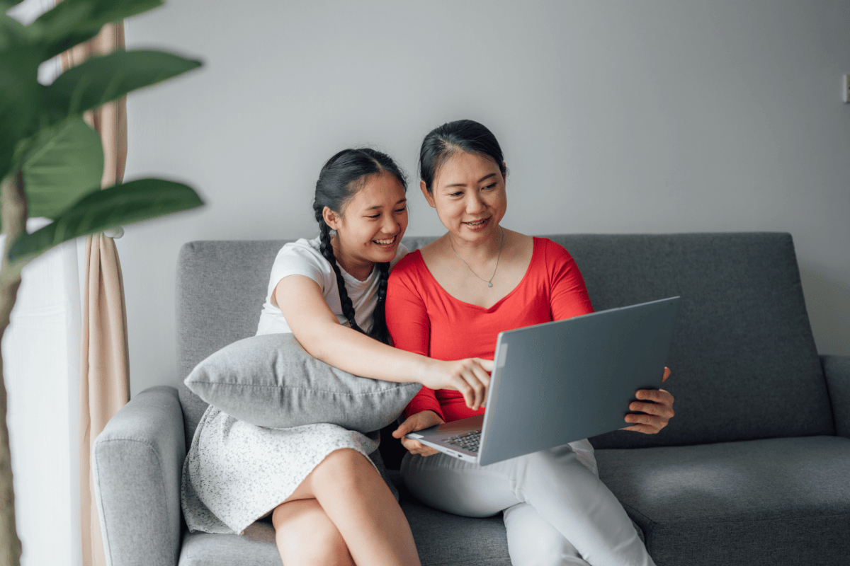 Mother and daughter smiling at laptop screen
