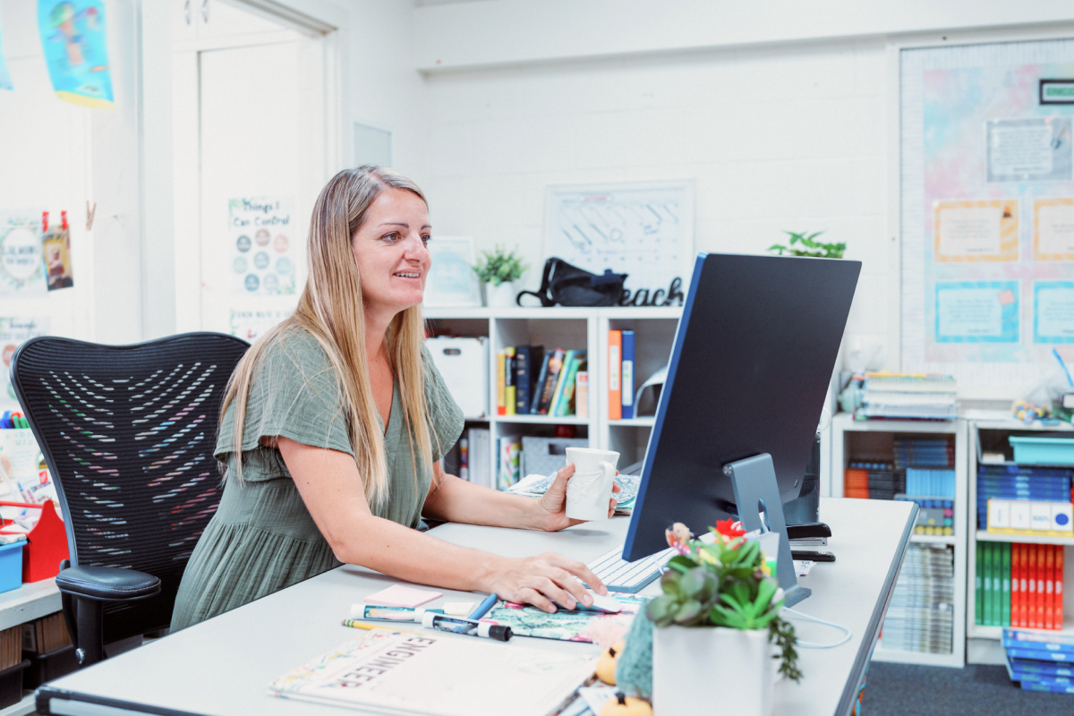 Educator working at classroom desk using computer