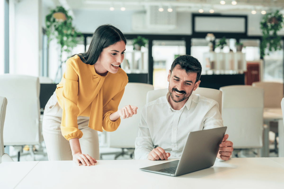 Two coworkers collaborating on a laptop in office